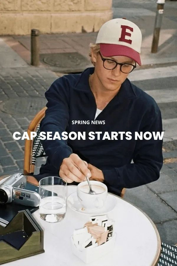 En mann sitter på en trekasse i et studio og bærer en klassisk brun cowboyhatt i filt med bred brem, en mørk denimskjorte og jeans.